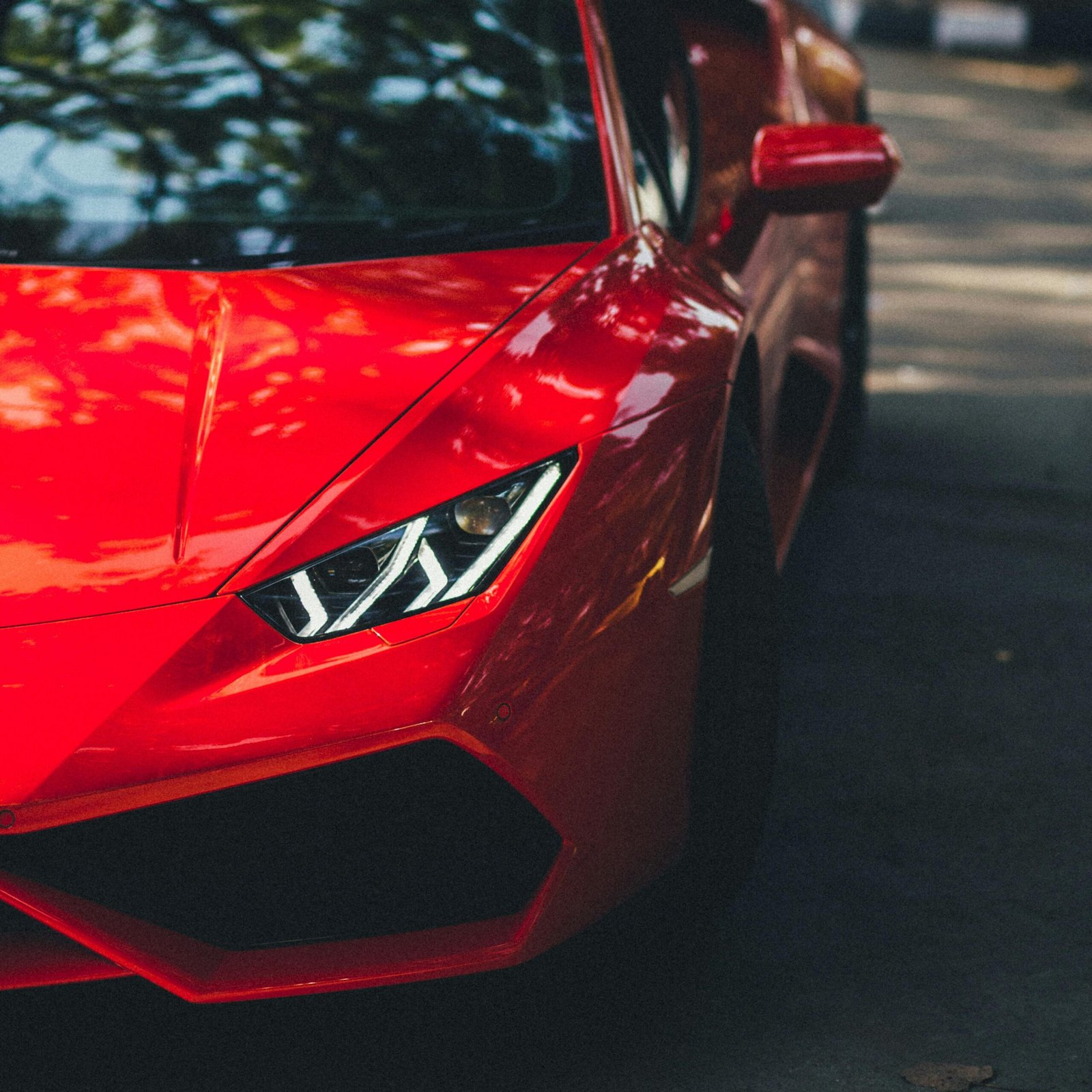 Striking image of a red Lamborghini Huracan parked on a sunny street in New Delhi, India.
