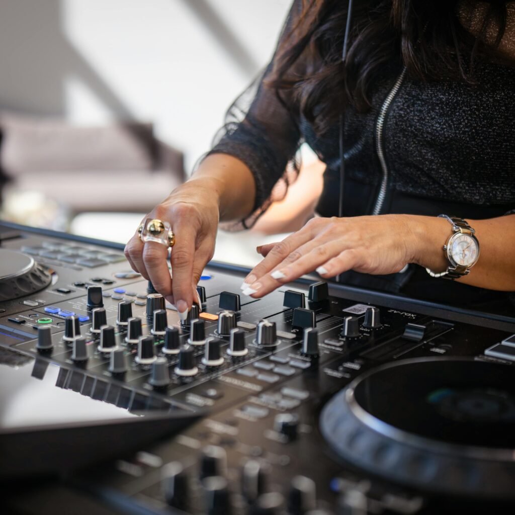 pexels photo 34237444 34237444 Close-up of a female DJ adjusting knobs on a soundboard during a live electronic music performance indoors.