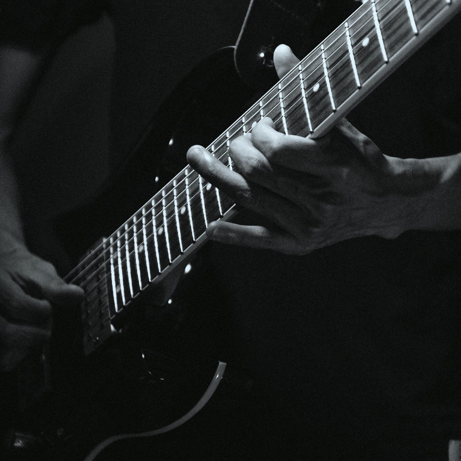 Moodful black and white photo capturing the art of playing electric guitar with a focus on skilled hands.